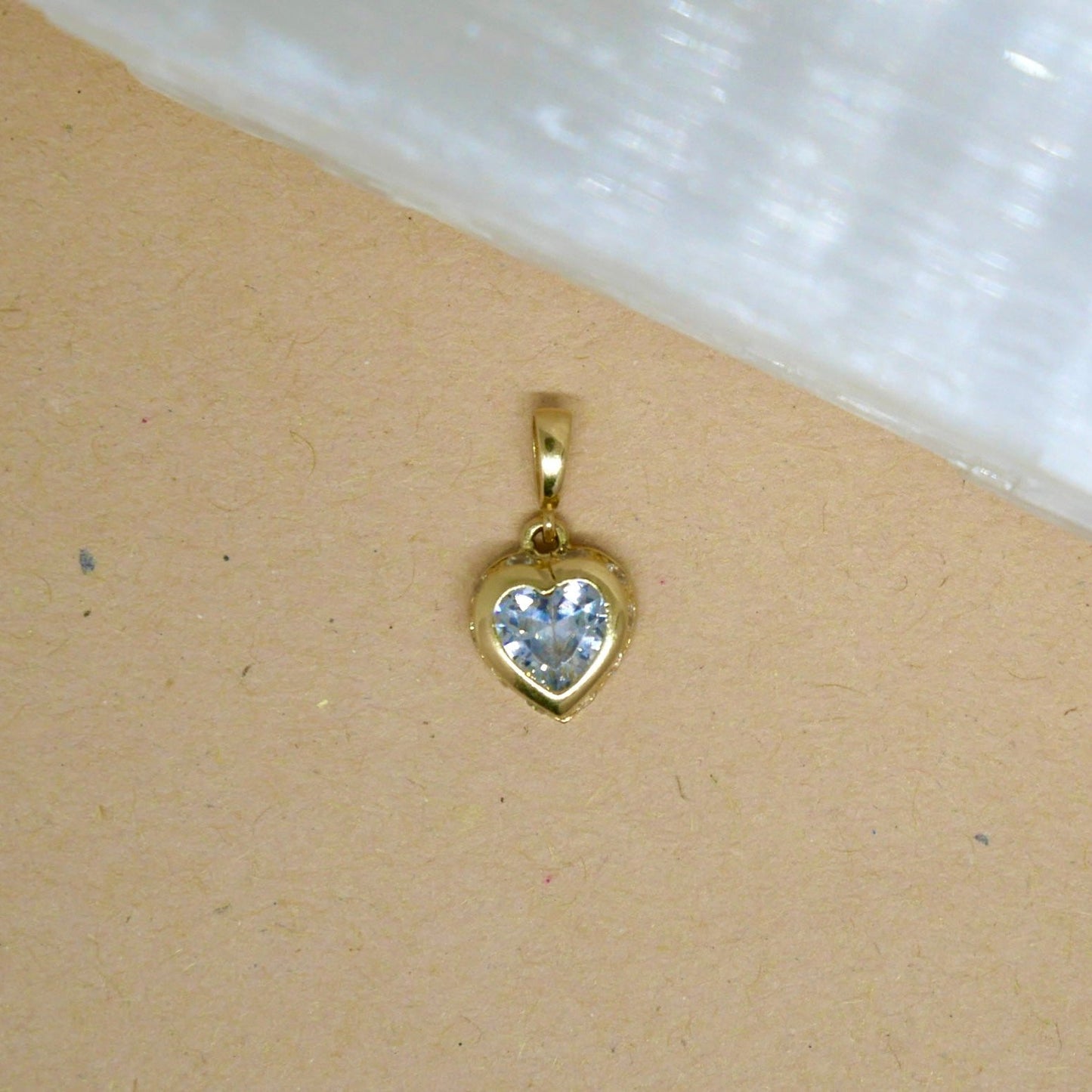 14k solid gold heart-shaped pendant featuring a vibrant white gemstone set in a smooth gold bezel, offering a beautiful contrast of color and elegance.