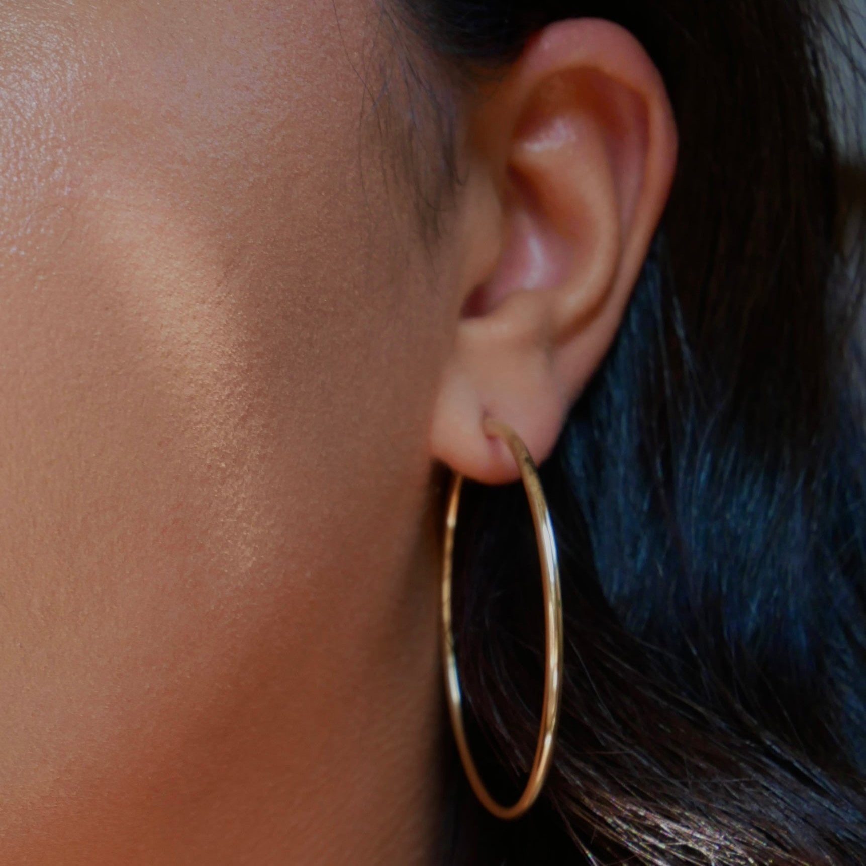 14k solid yellow gold large high-polished hoop earrings, 50mm diameter x 2mm width, featuring a sleek finish with a secure latch-back closure.