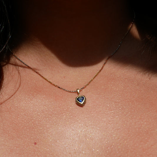 14k solid gold heart-shaped pendant featuring a vibrant blue gemstone set in a smooth gold bezel, offering a beautiful contrast of color and elegance.