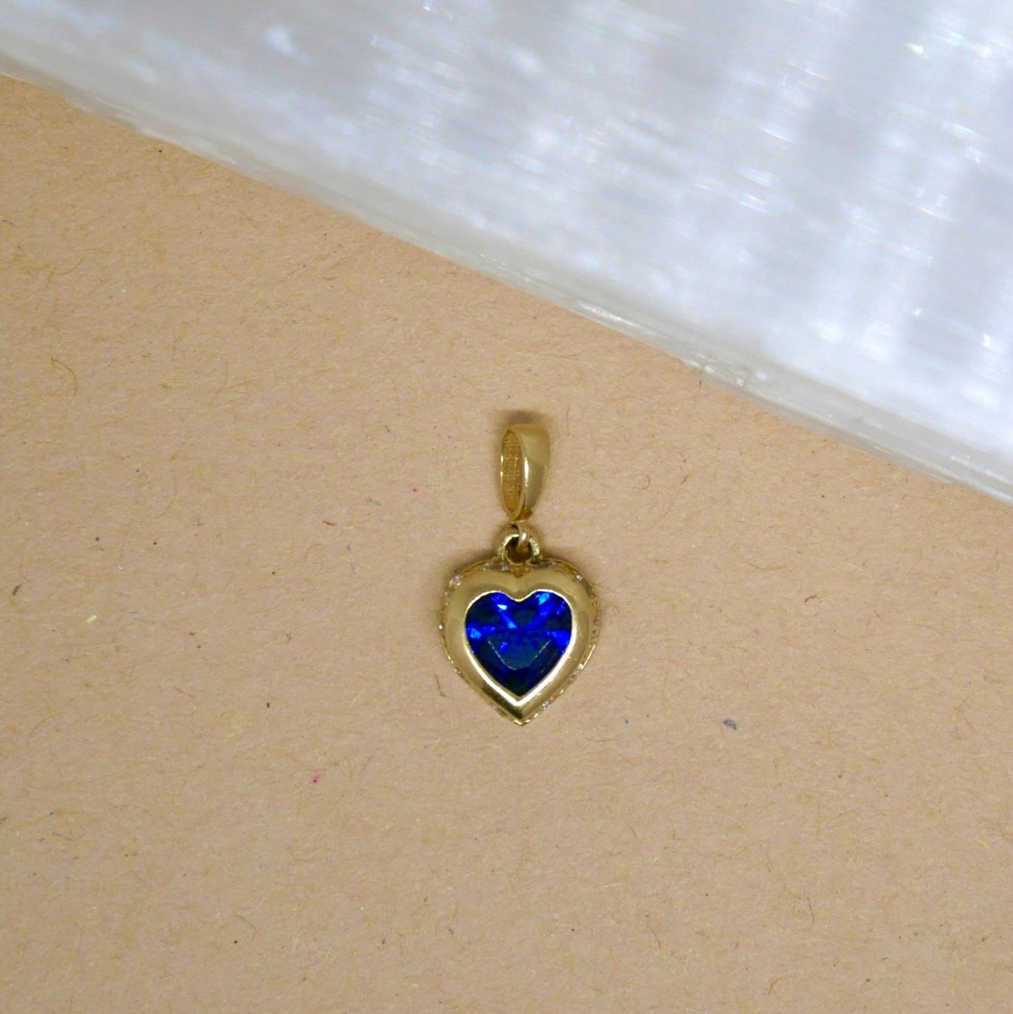 14k solid gold heart-shaped pendant featuring a vibrant blue gemstone set in a smooth gold bezel, offering a beautiful contrast of color and elegance.